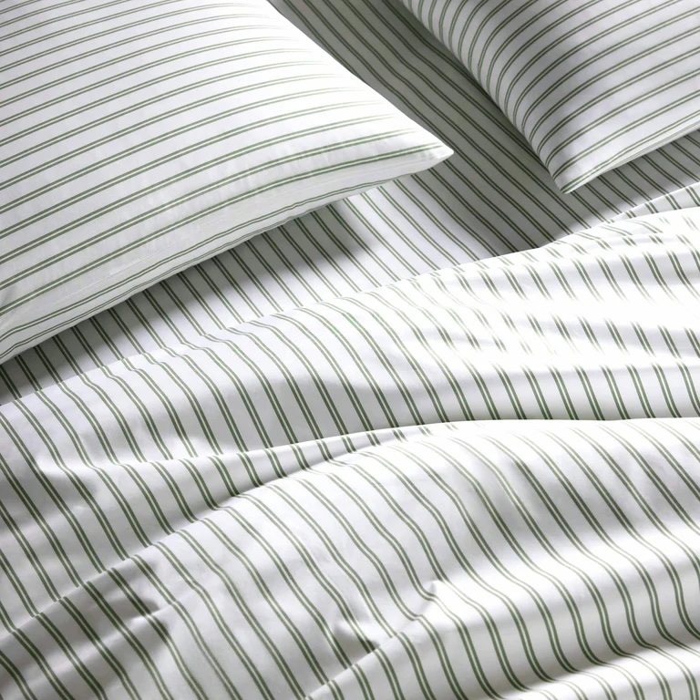Close-up of a neatly made bed with white sheets and pillowcases featuring thin green vertical and horizontal stripes.