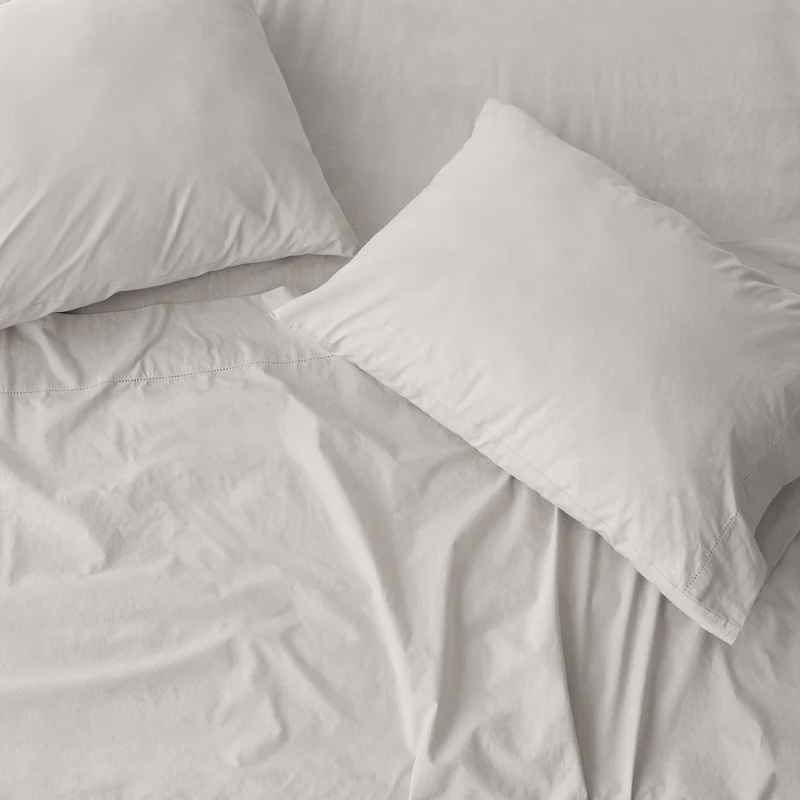 Two white pillows and a white sheet are arranged on a neatly made bed with minimal wrinkles.