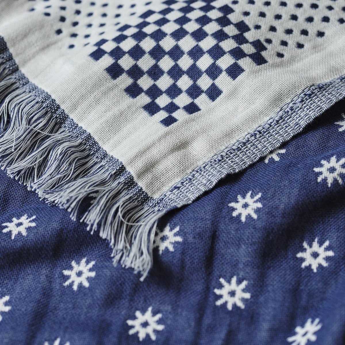 Close-up of two blue and white patterned textiles; one features fringe and a checkerboard design, while the other has a repeating snowflake-like motif.