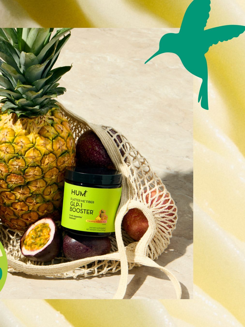A jar of HUM Nutrition GLOW Sweet Glow Booster, a great complement to fiber supplements for women, sits in a mesh bag with pineapple, passion fruits, and avocados on a beige surface. A green hummingbird graphic adorns the top right corner.