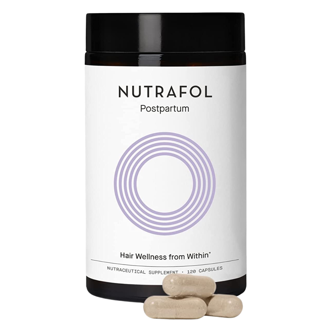 A bottle of Nutrafol Postpartum hair wellness supplement with three capsules placed in front of it.