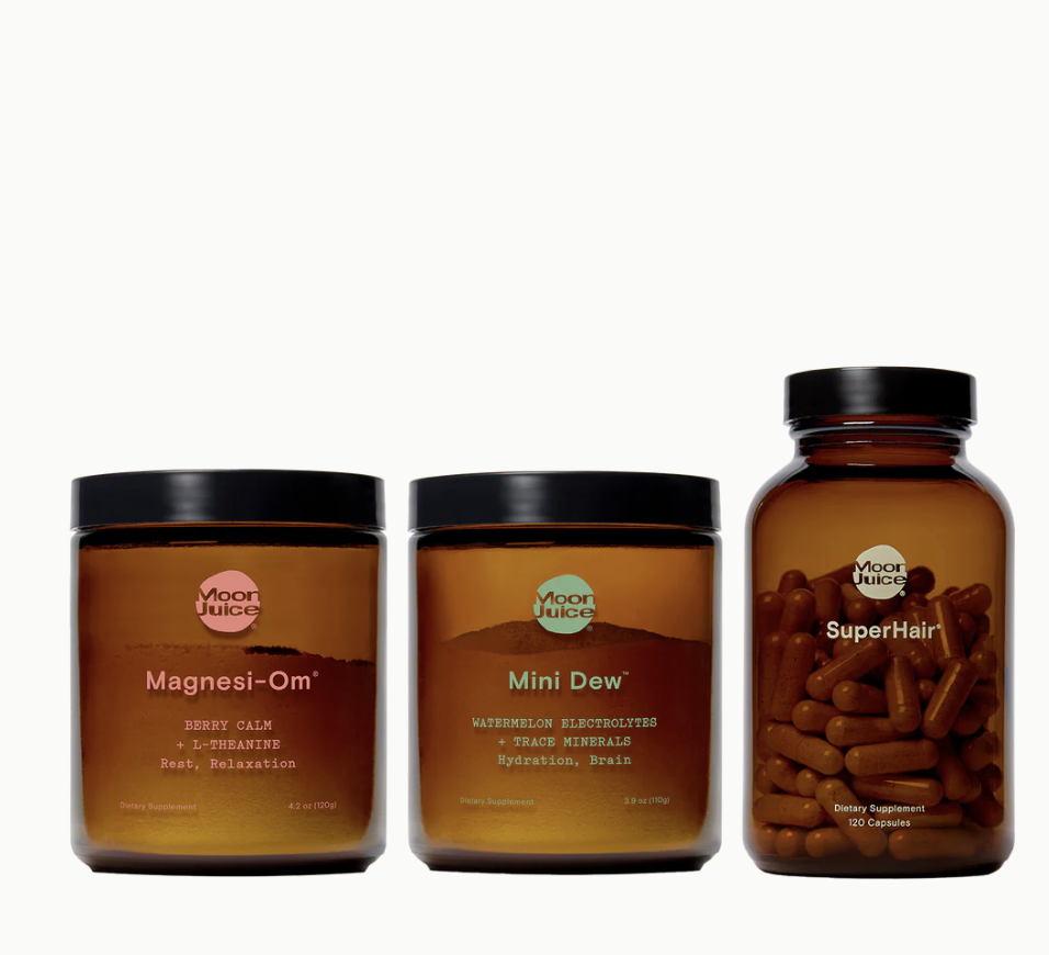 Three amber jars of Moon Juice supplements—Magnesi-Om, Mini Dew, and SuperHair—are displayed side by side on a white background.