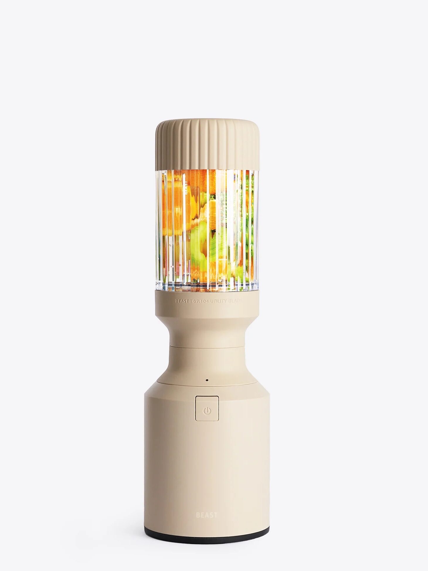 A beige portable blender filled with chopped fruits, including orange, green, and yellow pieces, stands upright against a plain white background.