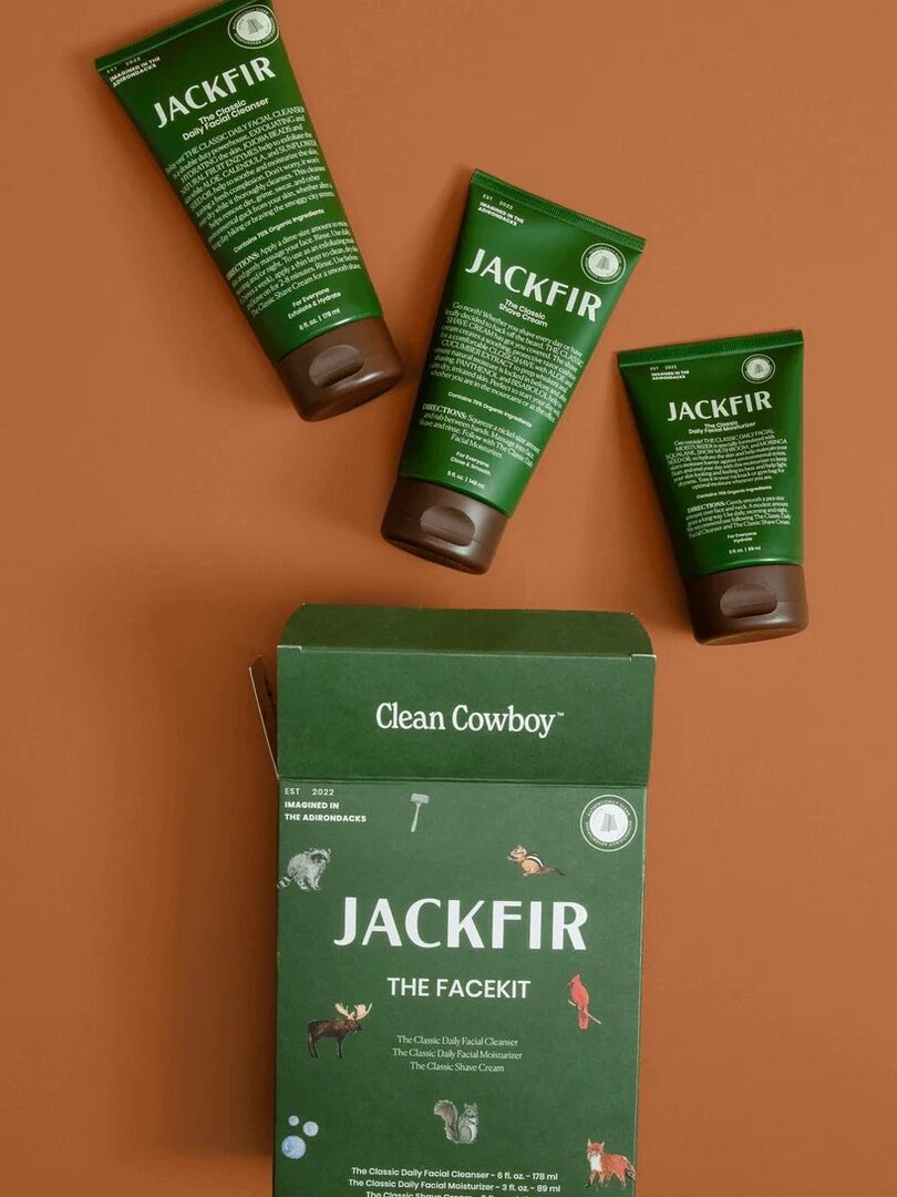 Three green Jackfir skincare tubes and a matching box labeled “The Facekit” are arranged on a brown background.