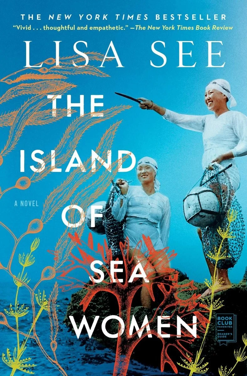 Two women in traditional diving attire stand on rocks holding fishing equipment, overlaid with illustrated sea plants and the book title "The Island of Sea Women" by Lisa See.
