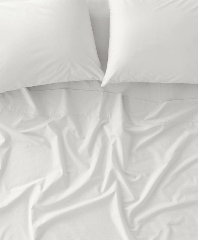 Two white pillows and a slightly wrinkled cooling sheet on a bed, viewed from above.