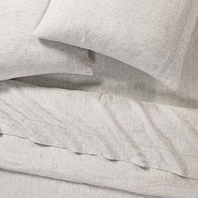 Light gray cooling sheets and pillowcases with a subtle heathered pattern, neatly arranged on a bed.