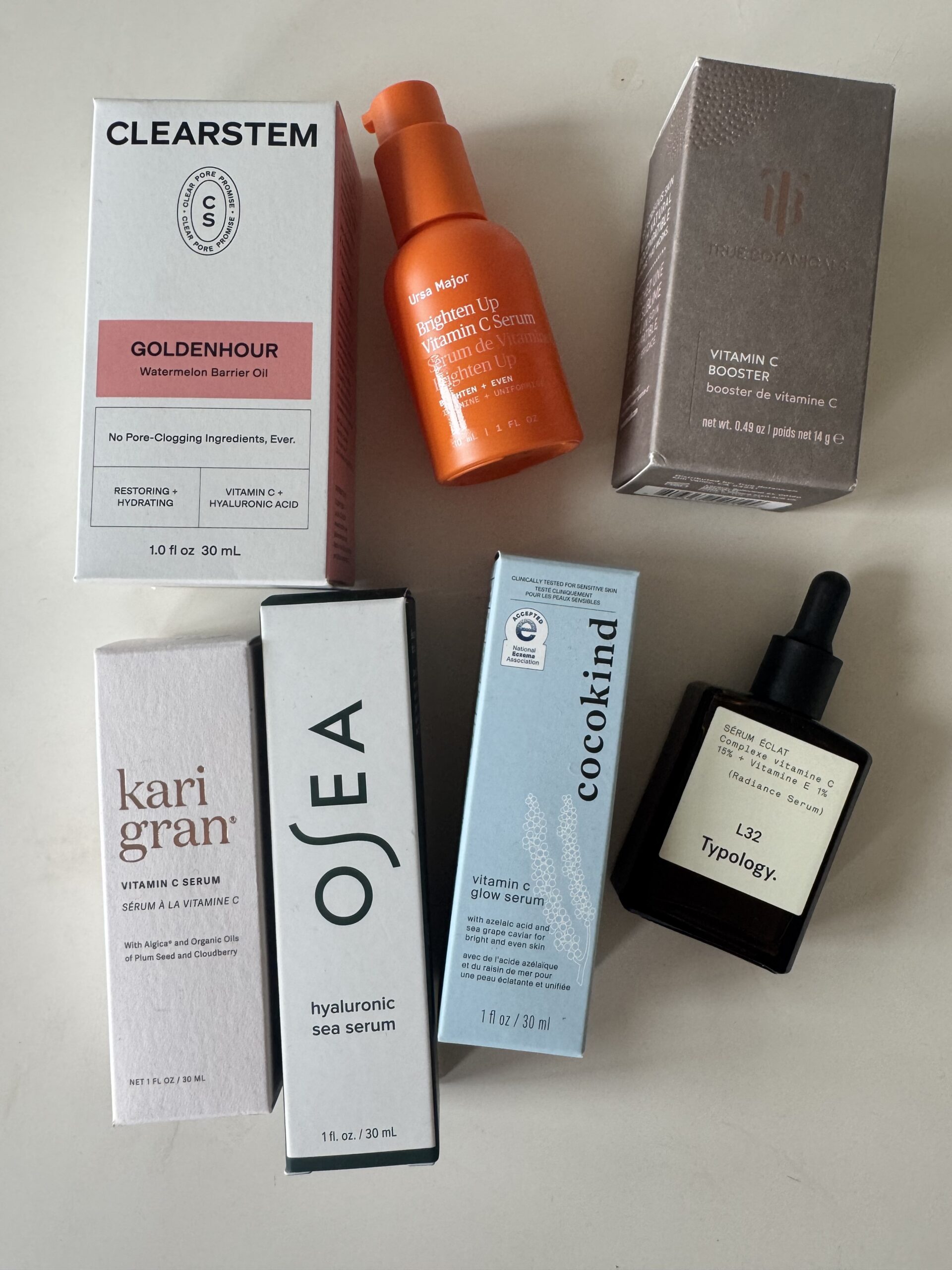 Six skincare serum and oil products from brands Clearstem, Osea, Kari Gran, Cocokind, Typology, and Ursa Major are arranged on a white surface.