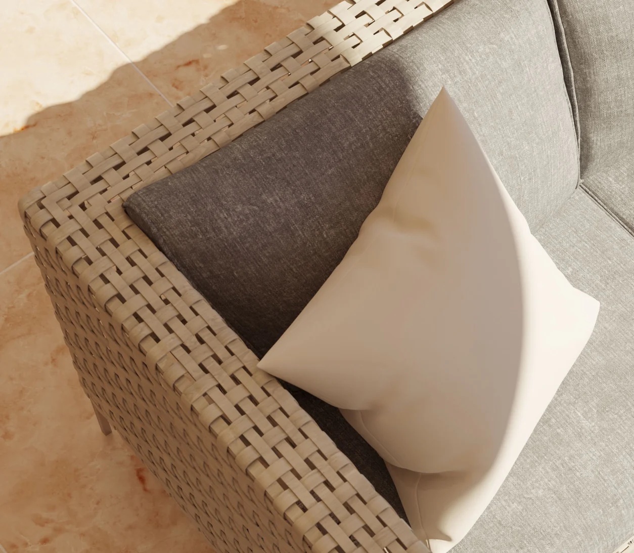A beige woven outdoor sofa features a gray cushion and a white throw pillow, positioned on a light-colored tiled floor in sunlight.