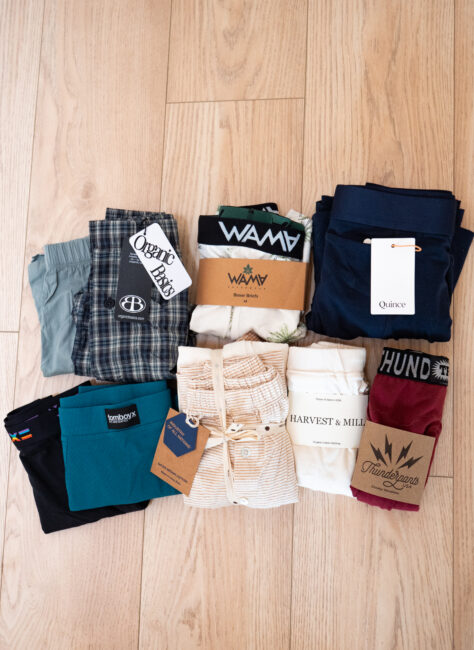 Nine folded pairs of men’s underwear and boxers from various brands are arranged in three rows on a light wooden floor.