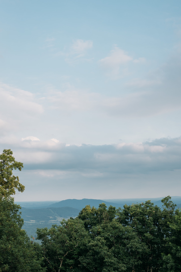 Distant mountains under a partly cloudy sky with green trees in the foreground.