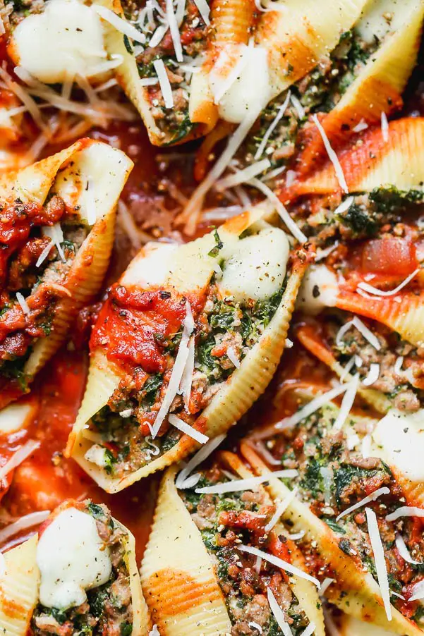 Stuffed pasta shells filled with spinach, ricotta, and meat, topped with tomato sauce and shredded cheese.