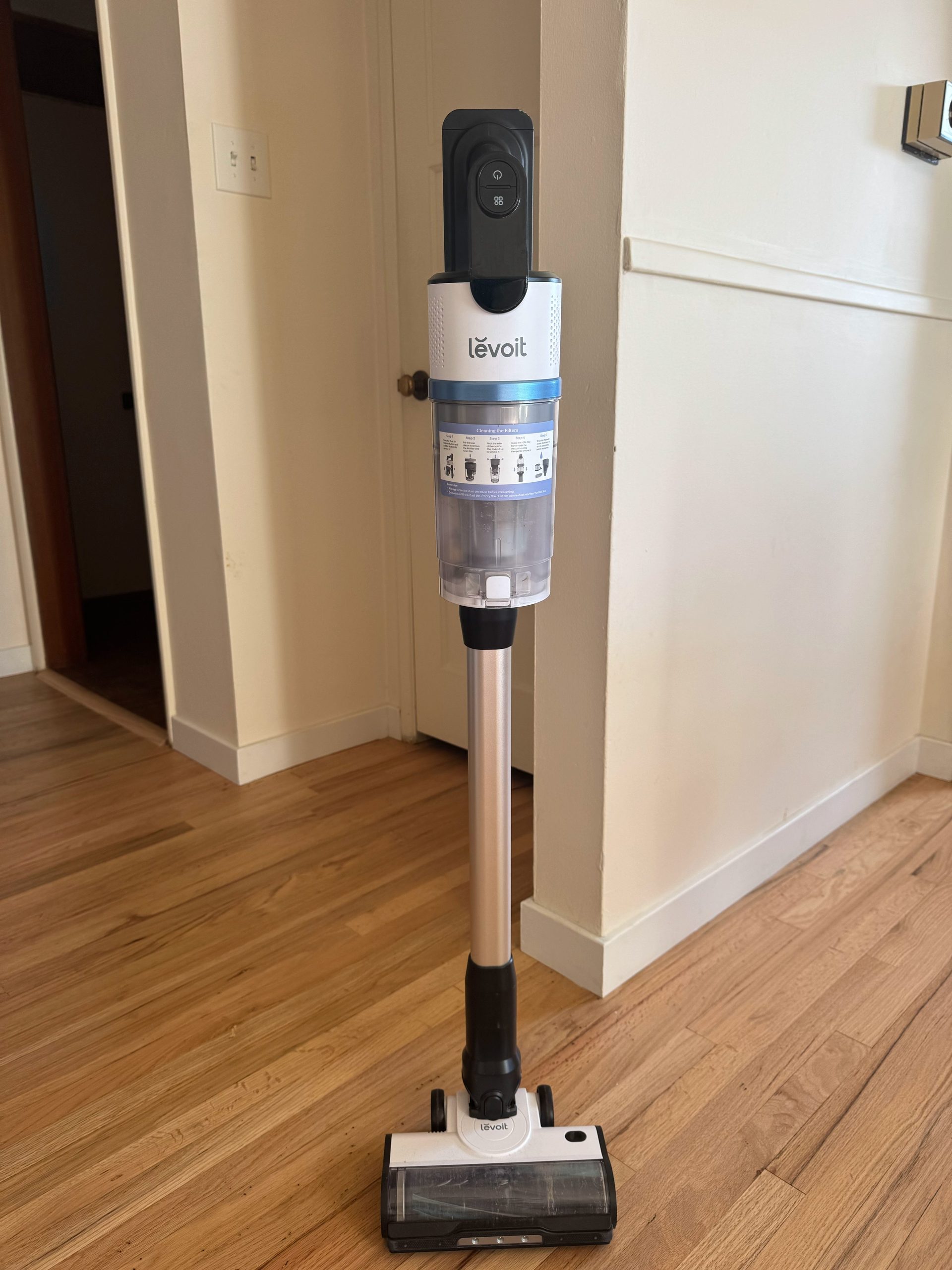 Levoit stick vacuum cleaner standing upright on a hardwood floor.