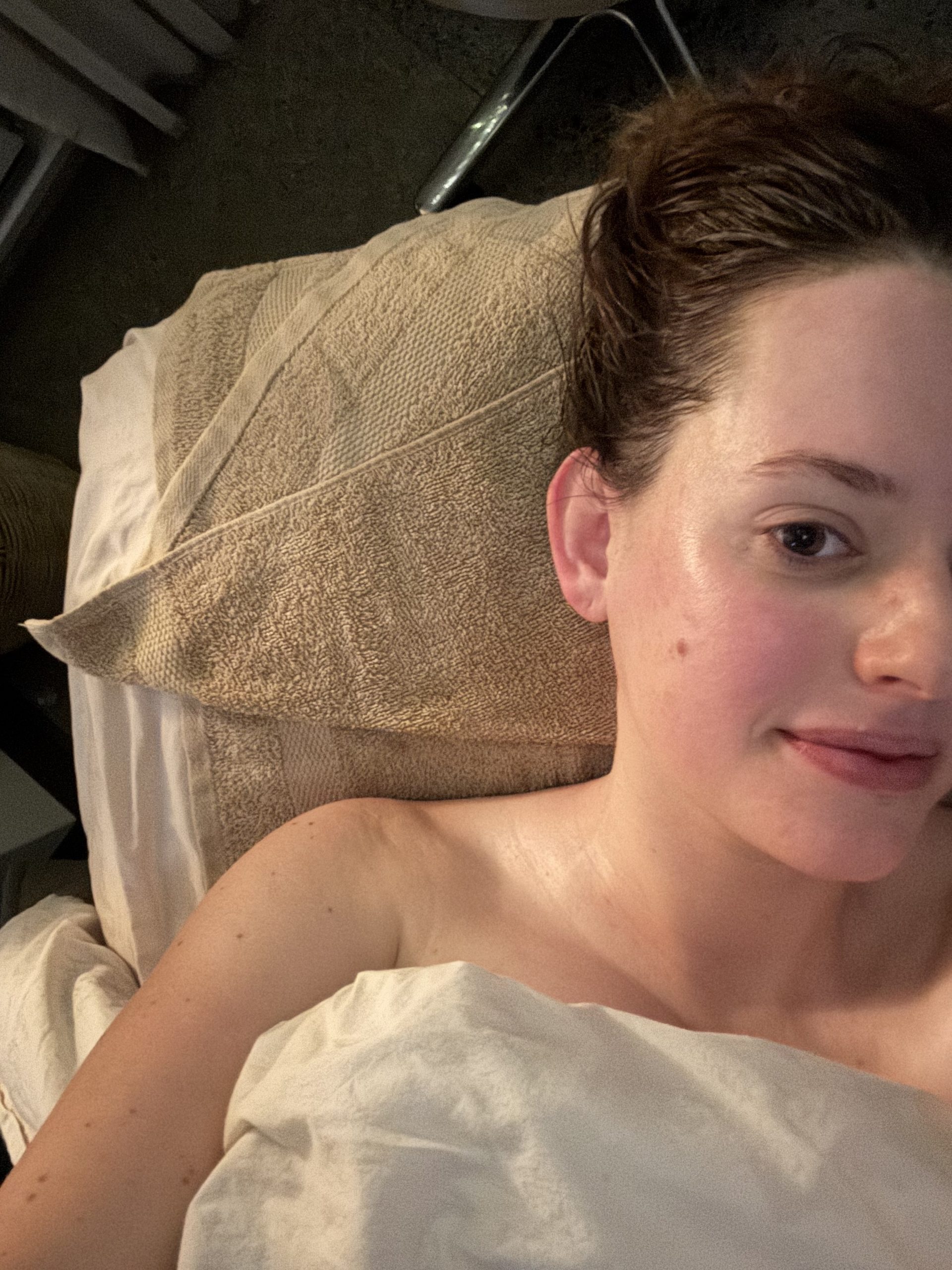 A woman lying on a spa treatment table with a towel tucked under her head.