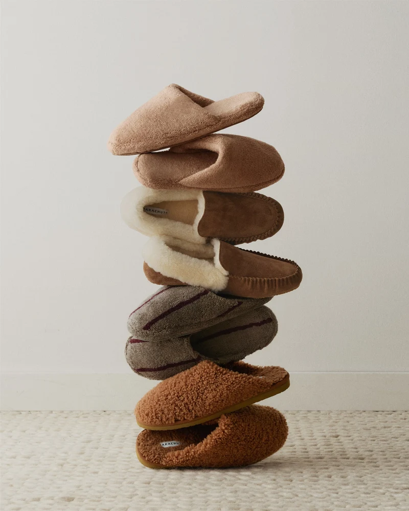A vertical stack of six assorted Parachute slippers.