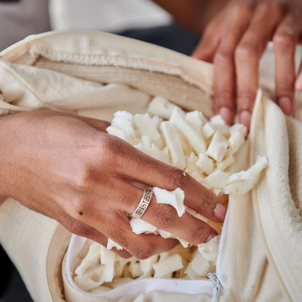 Hands opening a zippered pillow cover to reveal shredded foam filling.