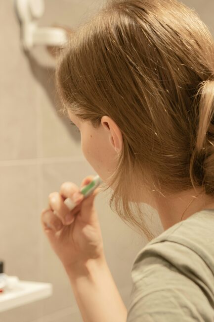 A person brushing their teeth in front of a mirror.